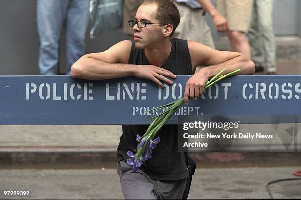 Man holds flowers behind police barricade outside Old St. Patrick's Cathedral during memorial service for John F. Kennedy Jr., his wife, Carolyn...