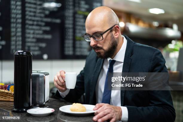 brazilian business man eating pao de queijo - cheese ball stock pictures, royalty-free photos & images