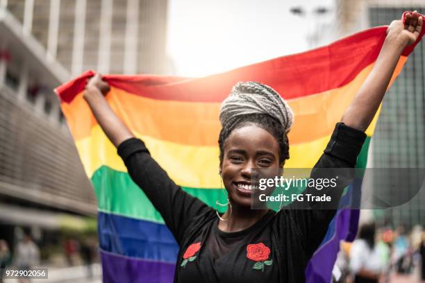 vrouw zwaaien regenboogvlag op gay parade - gay stockfoto's en -beelden