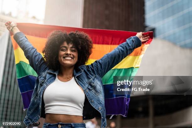 woman waving rainbow flag at gay parade - pride parade stock pictures, royalty-free photos & images