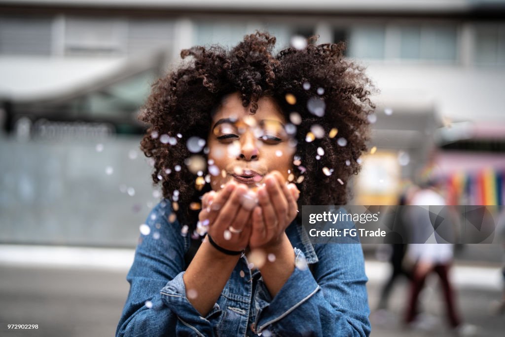 Portrait of cute woman blowing confetti