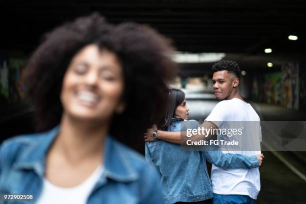 disloyal man with his girlfriend looking at another girl - cheating boyfriend stock pictures, royalty-free photos & images