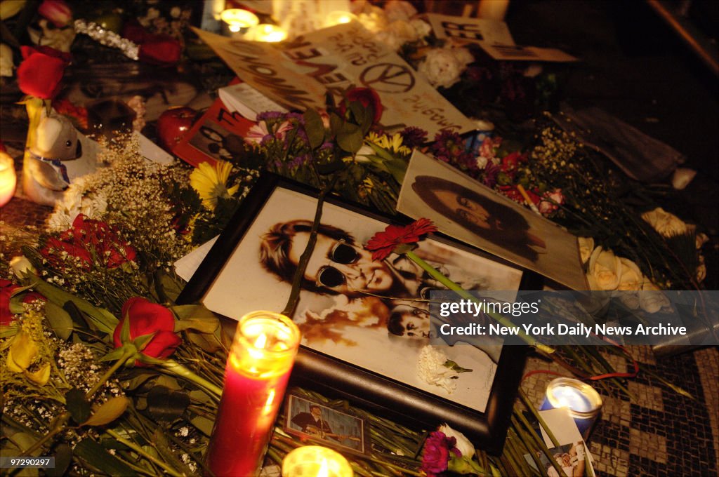 Candles, flowers, photographs and memorabilia cover the Imag