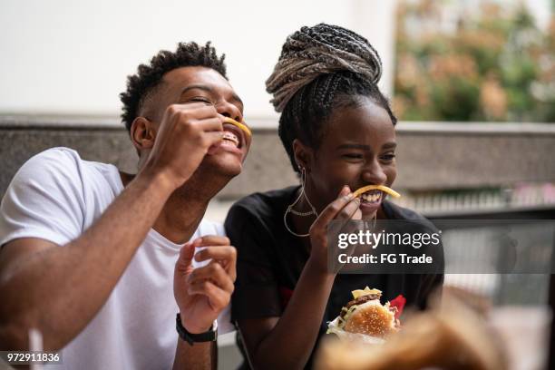 gruppe von jugendlichen, die spaß in einem restaurant - eating fast food stock-fotos und bilder