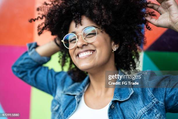 カラフルな背景を持つ女性の笑顔のポートレート - 2018 glasses ストックフォトと画像