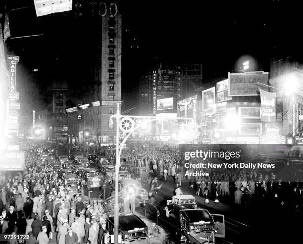 Times Square at night is aglitter with bright lights and filled with people.