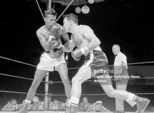 Carmen Basilio rips right hand at Ray Robinson in first round of middleweight bout at Yankee Stadium.
