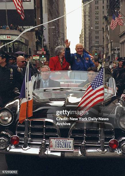 John Glenn and wife Annie greet crowd from open car in parade up lower Broadway honoring Glenn and crew of the Discovery space shuttle.