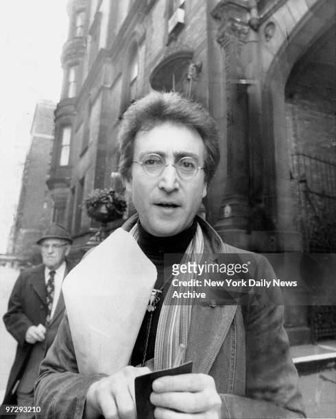John Lennon returning from florist shop outside his apartment at the Dakota.,