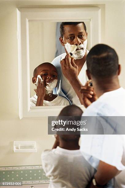 father shaving at mirror, son (6-8) putting on shaving foam - putting clothes son stock pictures, royalty-free photos & images