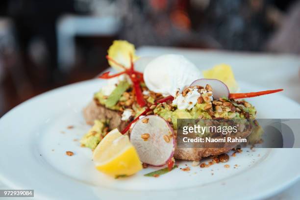 smashed avocado and poached eggs on sourdough bread - daylesford stockfoto's en -beelden