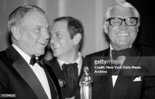 There's a twinkle in the eyes of Ol' Blue Eyes, Frank Sinatra, as he presents award to Cary Grant as Tony Curtis chuckles in background at Friars...