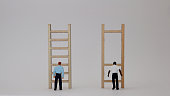Racist concepts in employment and promotion. Miniature people and miniature wooden ladders.