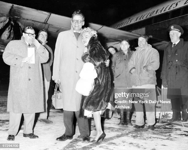 Marilyn Monroe cuddles on husband Arthur Miller at International Airport after arriving from a Jamaican vacation.