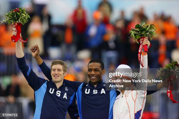 Speed skaters Joey Cheek of the U.S., fellow American Shani Davis and Erben Wennemars of the Netherlands hold up their bouquets at the flower...