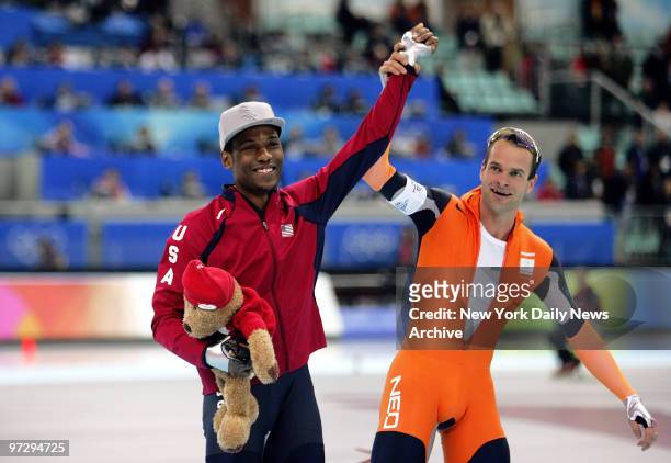 Speed skaters Shani Davis of the U.S. And Erben Wennemars of the Netherlands celebrate following the men's 1,000-meter race at the Oval Lingotto...