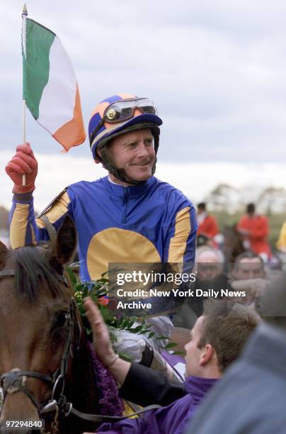 Jockey Michael Kinane waves an Irish flag after finishing alone to win the Breeders' Cup Juvenile race with bay colt Johannesburg at Belmont Park in...