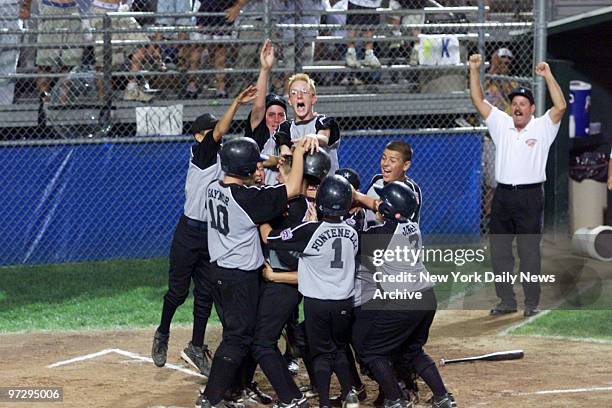New Jersey's Eric Campesi is mobbed by teammates after hitting a third-inning two-run homer against Massachusetts in the Little League East Region...