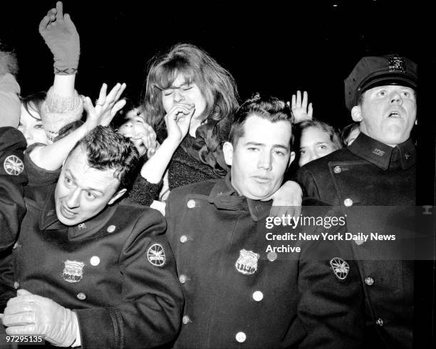 Frail barrier of policemen is swamped by suring beatlemaniacs as they spot their idols at Kennedy Airport. The Beatles flew in from Florida and then...