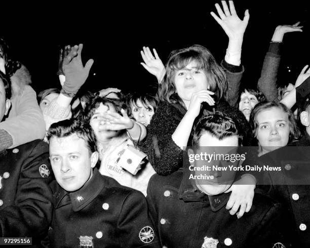 Frail barrier of policemen is swamped by suring beatlemaniacs as they spot their idols at Kennedy Airport. The Beatles flew in from Florida and then...
