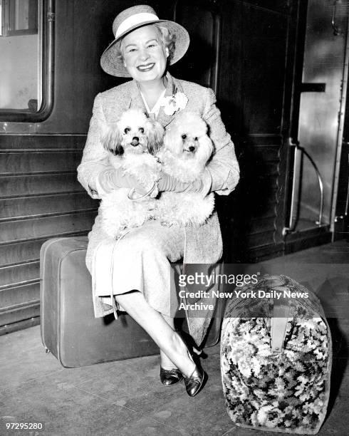 Shirley Booth, accompanied by her pet toy poodles, arrives at Grand Central Terminal after training in from Hollywood.