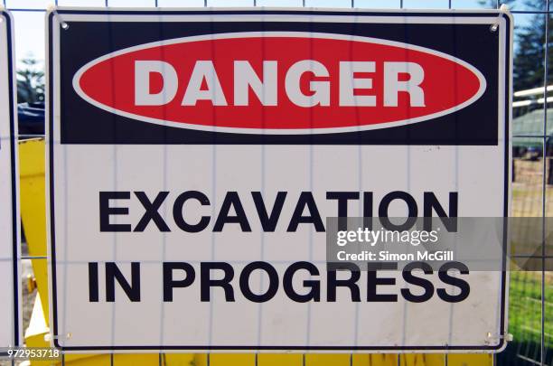 'danger: excavation in progress' sign on a fence around a construction site - bord gevaar stockfoto's en -beelden