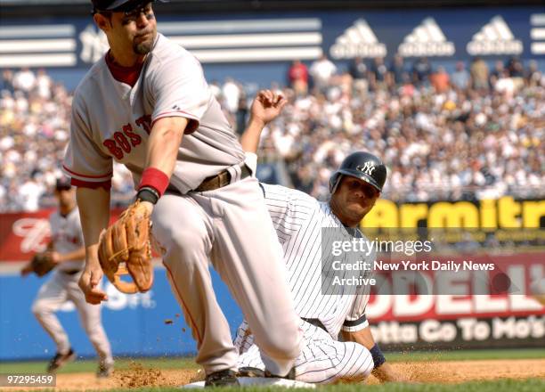 New Yankees' Bobby Abreu slides in safely to steal third as Boston Red Sox's third baseman Mike Lowell reaches to his right for a wide throw from the...