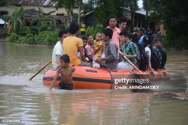 Indian villagers ride a rubber boat on a flooded street during heavy rain showers in Mogpara village, some 137 km south of Agartala, the capital of...