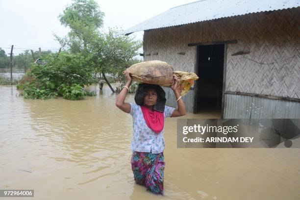 An Indian tribal resident carries belongings over her head on a flooded street during heavy rain showers in Mogpara village, some 137 km south of...