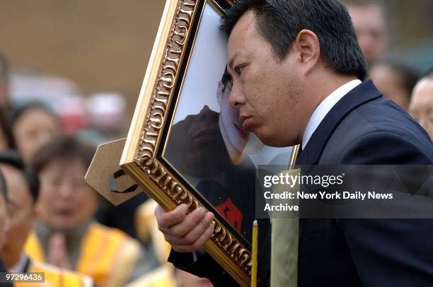 Mark Jiang holds a framed picture of his 10-year-old son, Douglas Jiang, as his coffin is loaded into a hearse outside the Central Funeral Home in...