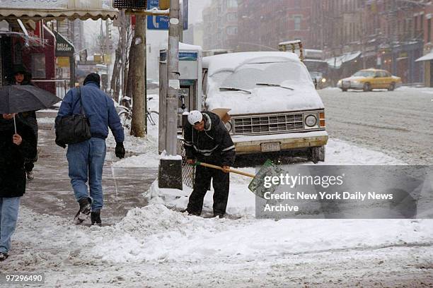 Shoveler makes a path through the snow and slush at 46th St. And Ninth Ave.