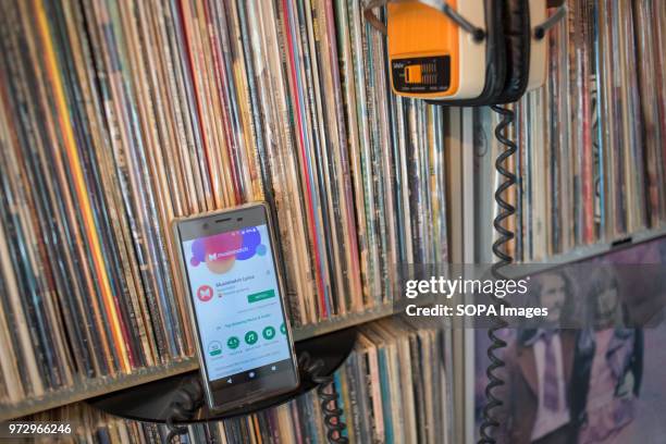 In this photo illustration, the Musixmatch Lyrics application seen displayed on an Android Sony smartphone front of hundreds of old 33rpm vinyls.