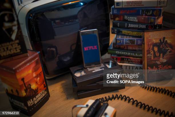 In this photo illustration, the Netflix application seen displayed on an Android Sony smartphone surrounded by old videotapes.