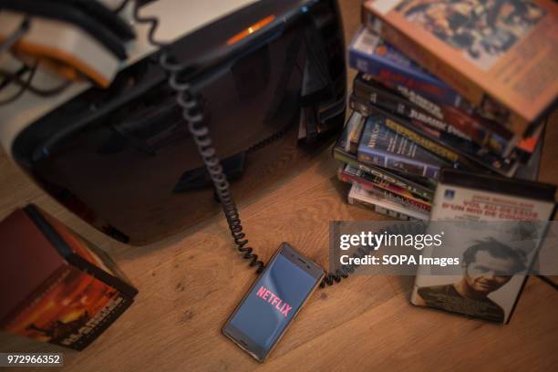 In this photo illustration, the Netflix application seen displayed on an Android Sony smartphone surrounded by old videotapes.