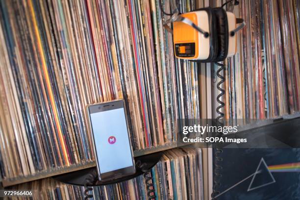 In this photo illustration, the Musixmatch Lyrics application seen displayed on an Android Sony smartphone front of hundreds of old 33rpm vinyls.