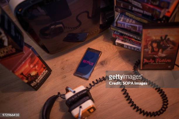 In this photo illustration, the Netflix application seen displayed on an Android Sony smartphone surrounded by old videotapes.