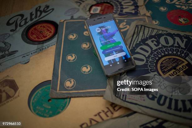 In this photo illustration, the Spotify application seen displayed on an Android Sony smartphone surrounded by old 78rpm vinyls.