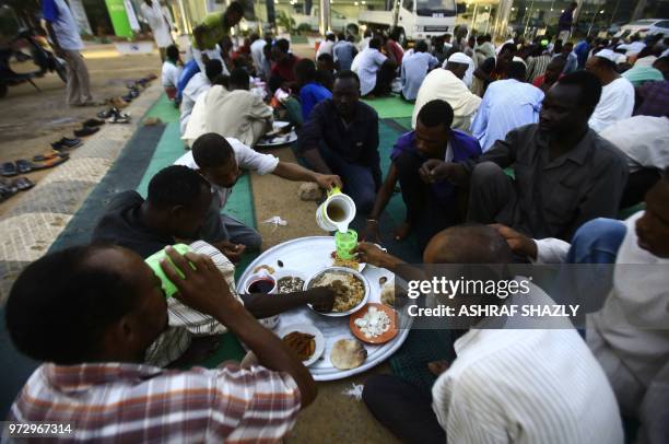 Sudanese break their fast along a highway in Khartoum on June 12, 2018. - Muslims around the world celebrate the holy month of Ramadan by praying...