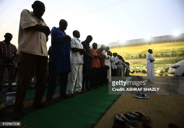 Sudanese offer evening prayers along a highway in Khartoum on June 12, 2018. - Muslims around the world celebrate the holy month of Ramadan by...