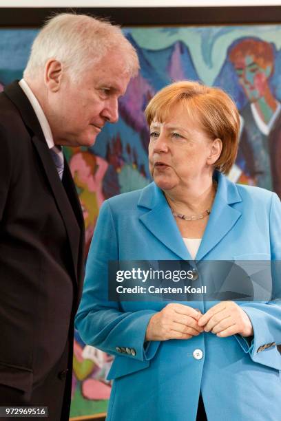 German Chancellor Angela Merkel speaks to German Interior Minister Horst Seehofer after the arrival for the weekly government cabinet meeting on June...