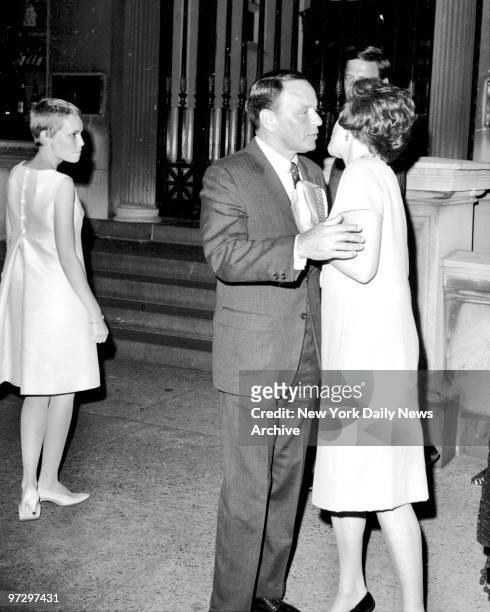 Frank Sinatra embraces a lady fan while his bride, Mia Farrow looks on, keeping a stiff upper lip. The honeymooners were leaving the 21 Club on W....