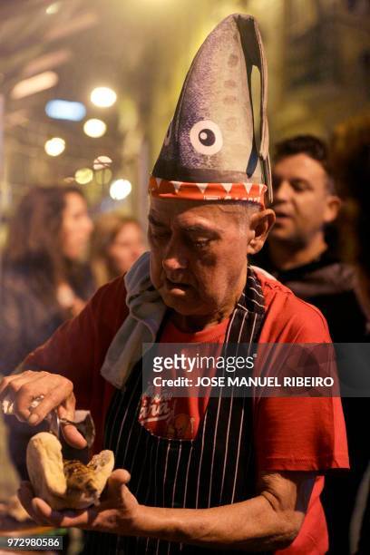 Cook places a sardine on a bread bun during the Santo Antonio de Lisboa's Parade on Avenida da Liberdade, in Lisbon on June 12, 2018. - Lisbon...