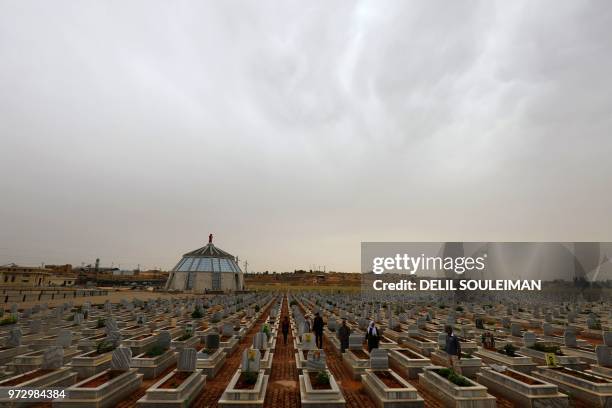 Syrian Kurds visit on May 28, 2018 the tombs of loved ones at a cemetery set up in 2012 which houses the remains of civilians and fighters who lost...