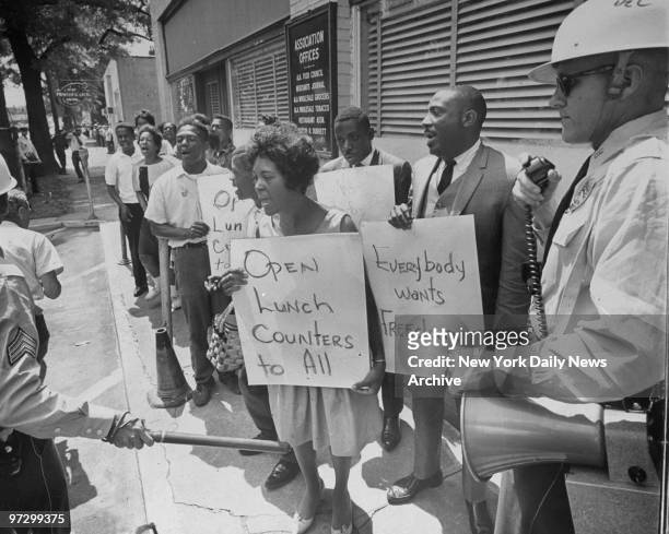 Singer Dick Gregory holds sign reading "Everybody wants Freedom," as he leads demonstrators to jail while police look on in Birmingham, Ala.,