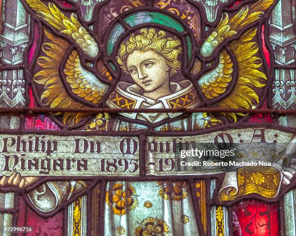 Close-up of stained glass at the Saint James Cathedral. The image has an angel holding a sign reading 'Philip Du Moulin'.