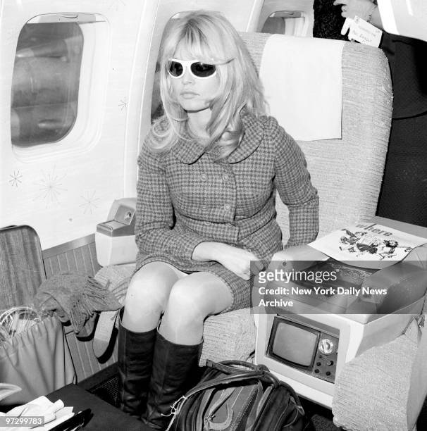 French sex kitten Brigitte Bardot, wearing dark glasses to soothe her irritated winking eye, sits in plane at Newark Airport before flying out to...