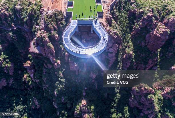 Aerial view of tourists walking on the glass skywalk at Fuxi Mountain tourism area on June 12, 2018 in Xinmi, Henan Province of China. The round...