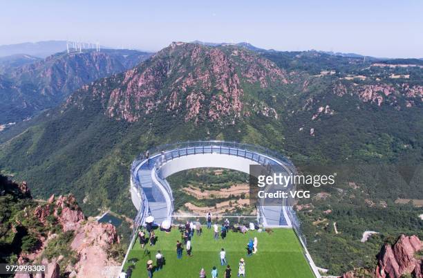 Aerial view of tourists walking on the glass skywalk at Fuxi Mountain tourism area on June 12, 2018 in Xinmi, Henan Province of China. The round...