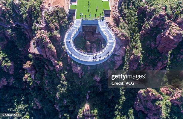 Aerial view of tourists walking on the glass skywalk at Fuxi Mountain tourism area on June 12, 2018 in Xinmi, Henan Province of China. The round...