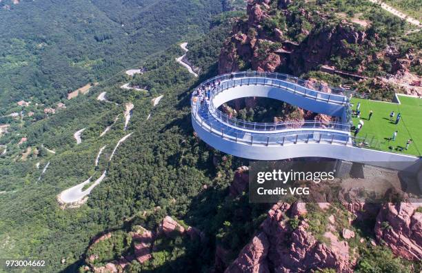 Aerial view of tourists walking on the glass skywalk at Fuxi Mountain tourism area on June 12, 2018 in Xinmi, Henan Province of China. The round...